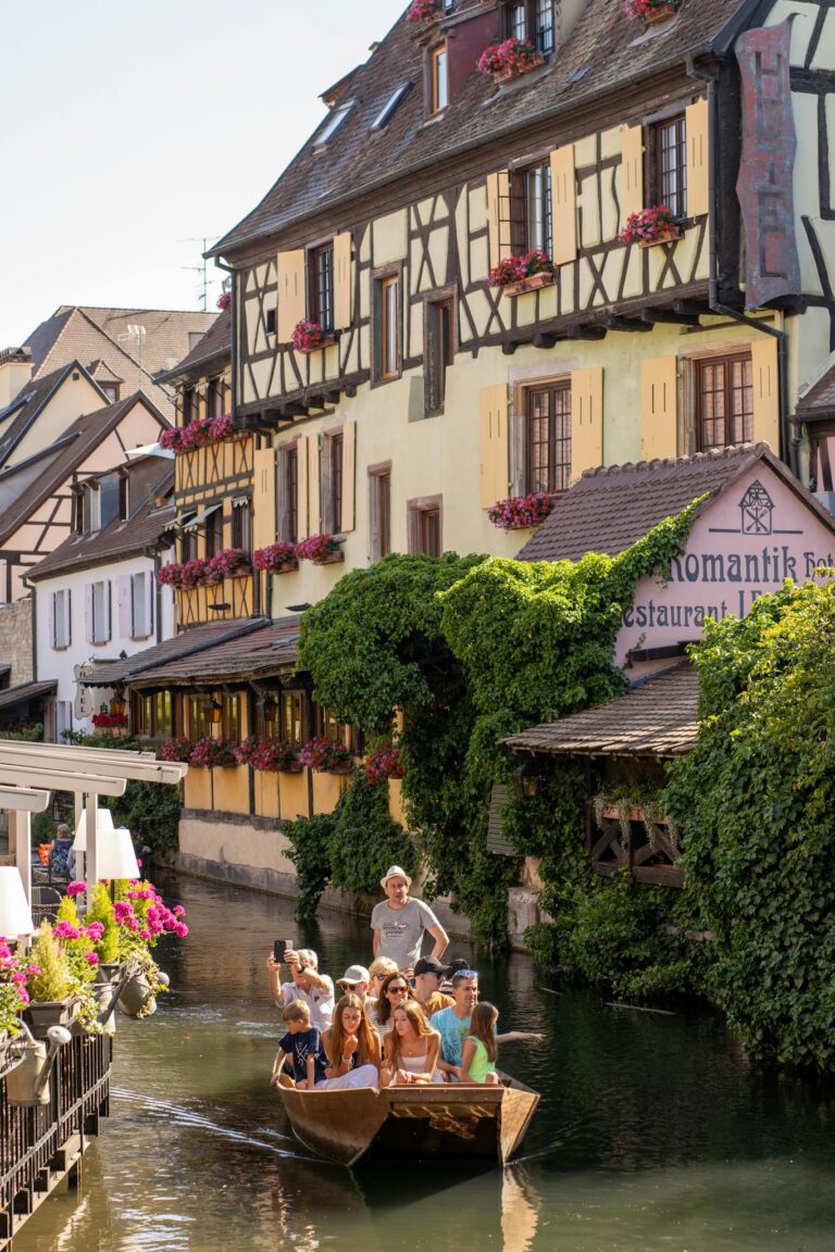 Family enjoying a scenic boat ride along a picturesque canal in Colmar, France.