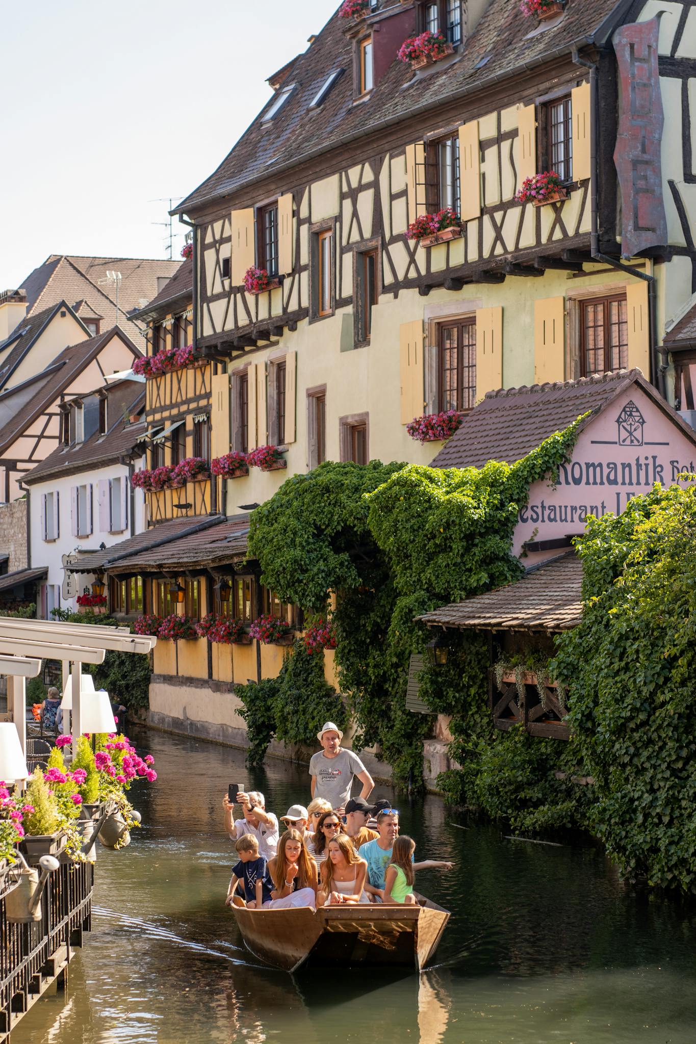 Family enjoying a scenic boat ride along a picturesque canal in Colmar, France.