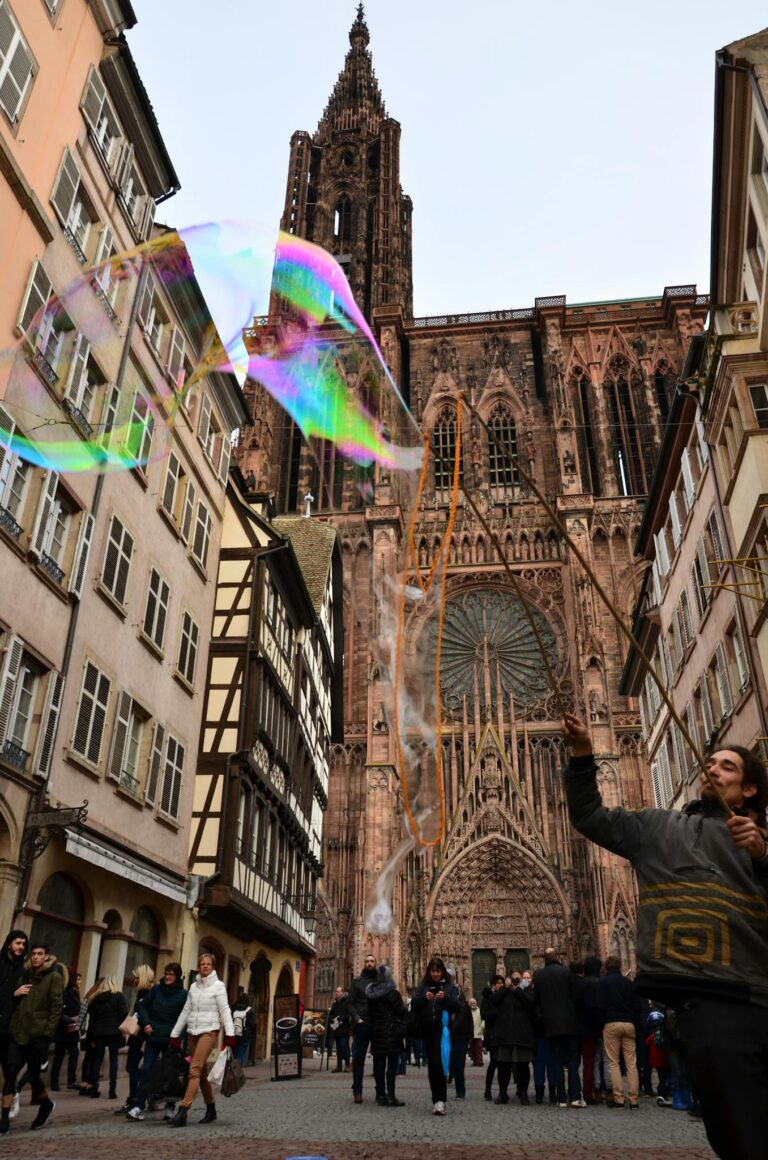 Street view of Strasbourg Cathedral with a performer making bubbles, capturing the urban ambiance.